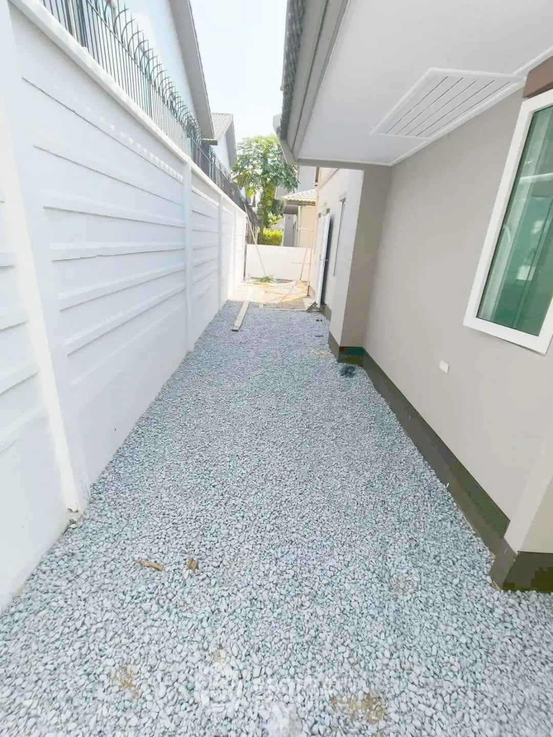 Modern residential exterior with gravel pathway and secure fencing
