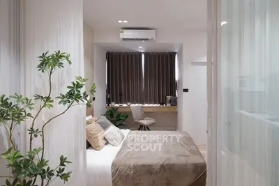 Modern bedroom with cozy decor and natural light, featuring a workspace and air conditioning.