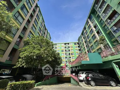 Vibrant multi-story residential building with parking area and lush greenery.