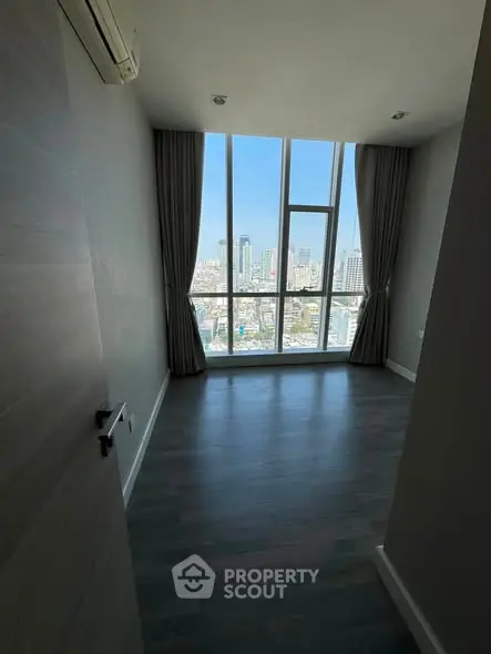 Spacious room with floor-to-ceiling windows offering stunning city views, perfect for modern living.