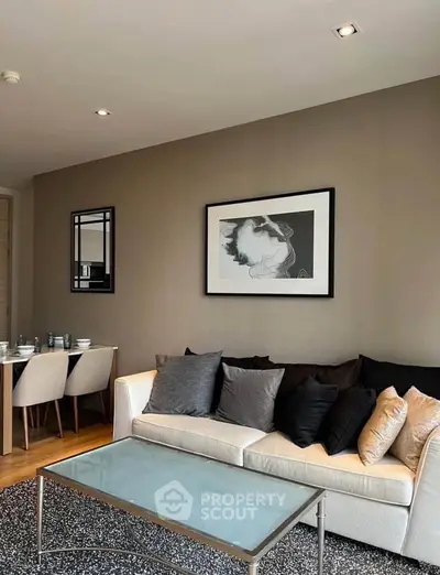 Modern living room with stylish decor and dining area, featuring a comfortable sofa and elegant artwork.