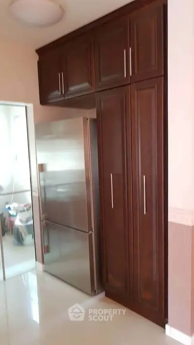 Modern kitchen with sleek stainless steel fridge and elegant wooden cabinetry.
