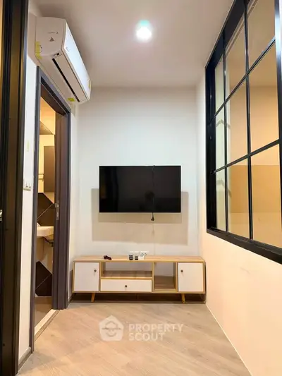 Modern living room with wall-mounted TV and sleek air conditioning unit, perfect for cozy urban living.