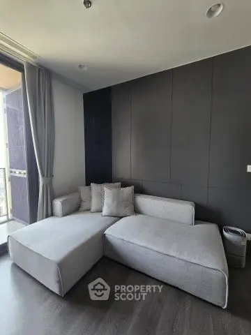 Modern living room with sleek gray sofa and floor-to-ceiling windows for natural light.