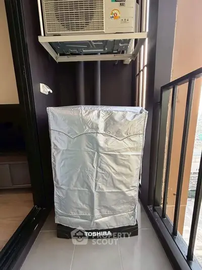 Compact balcony with air conditioning unit and covered washing machine, ideal for urban living.