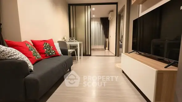 Modern living room with festive decor and sleek TV setup in cozy apartment.