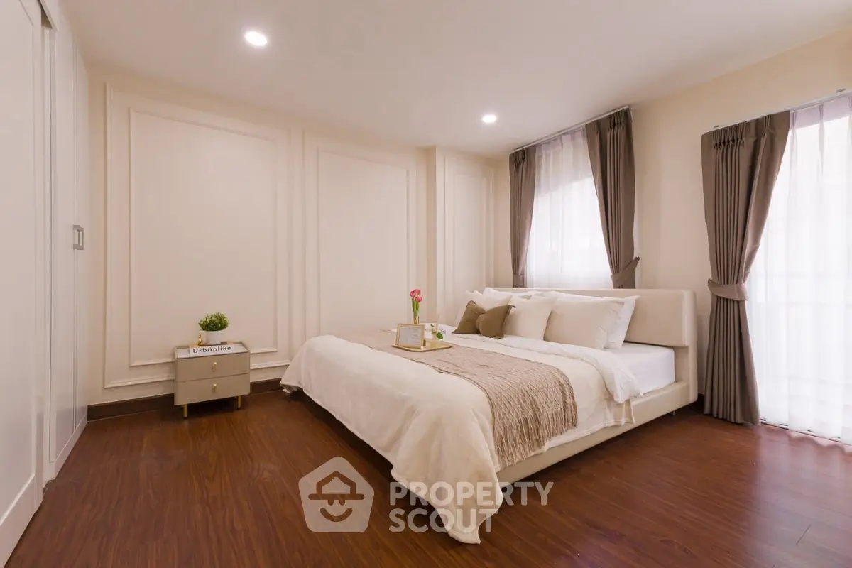 Elegant bedroom with cozy decor and natural light, featuring a stylish bed and wooden flooring.