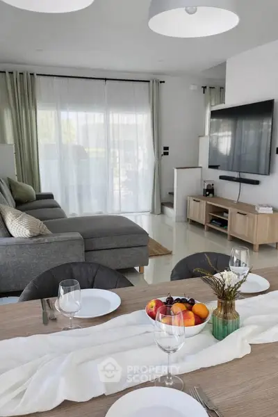 Modern living room with sleek furniture and large TV, perfect for entertaining guests.