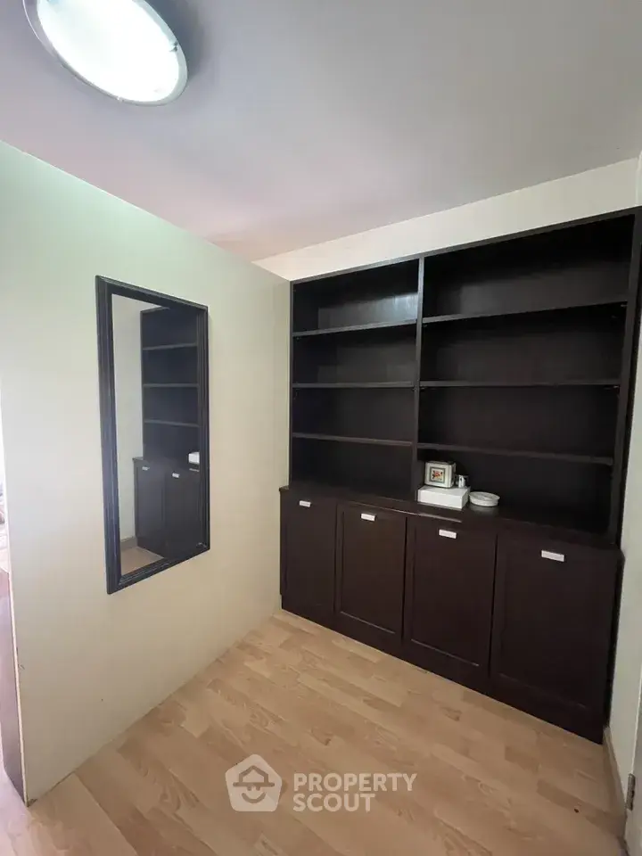 Spacious study room with built-in dark wood shelves and mirror, perfect for home office setup.