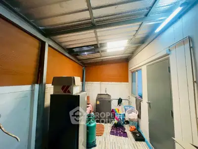 Compact storage room with metal roof and various household items