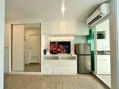 Modern living room with sleek design, featuring built-in storage, TV, and stainless steel appliances.