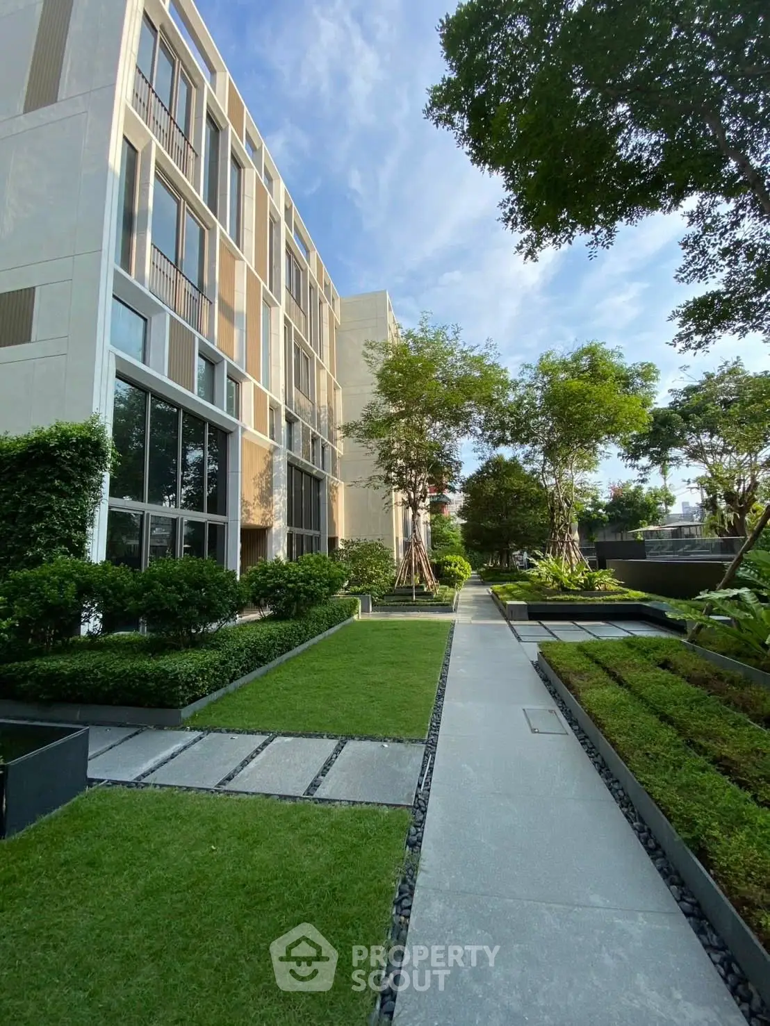 Luxurious modern building with lush garden and pathway, perfect for serene living.