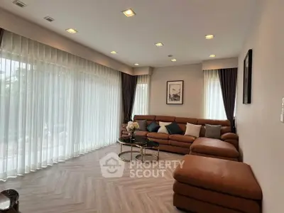 Luxurious living room with elegant brown leather sofa and floor-to-ceiling windows.