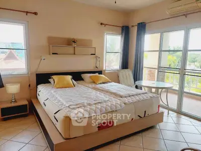 Spacious bedroom with large windows and balcony access, offering a bright and airy atmosphere.