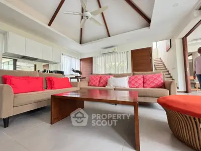 Spacious living room with modern decor and high ceiling, featuring cozy sofas and a wooden coffee table.