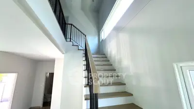 Elegant staircase with modern railing and natural light in a spacious home interior.