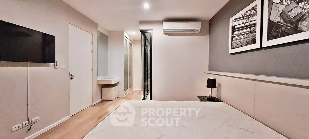 Modern bedroom with minimalist design, featuring a mounted TV, air conditioning, and stylish decor.