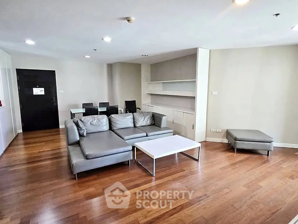 Spacious modern living room with sleek furniture and wooden flooring in a contemporary apartment.