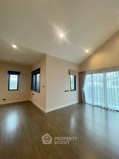 Spacious empty room with large windows and wooden flooring, ideal for customization.