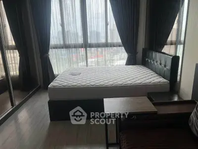 Spacious bedroom with large windows and modern furnishings in a high-rise apartment.