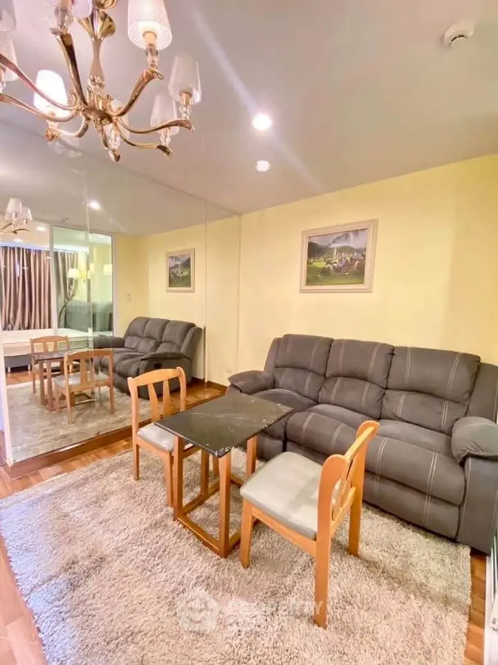 Cozy living room with plush sofa, elegant chandelier, and mirrored wall for spacious feel.