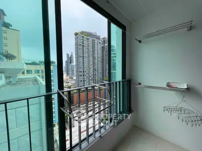 High-rise apartment balcony with city view and laundry rack, perfect for urban living.