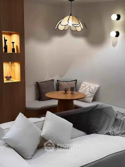 Cozy modern living room with elegant lighting and stylish decor, featuring a comfortable seating area and decorative shelves.