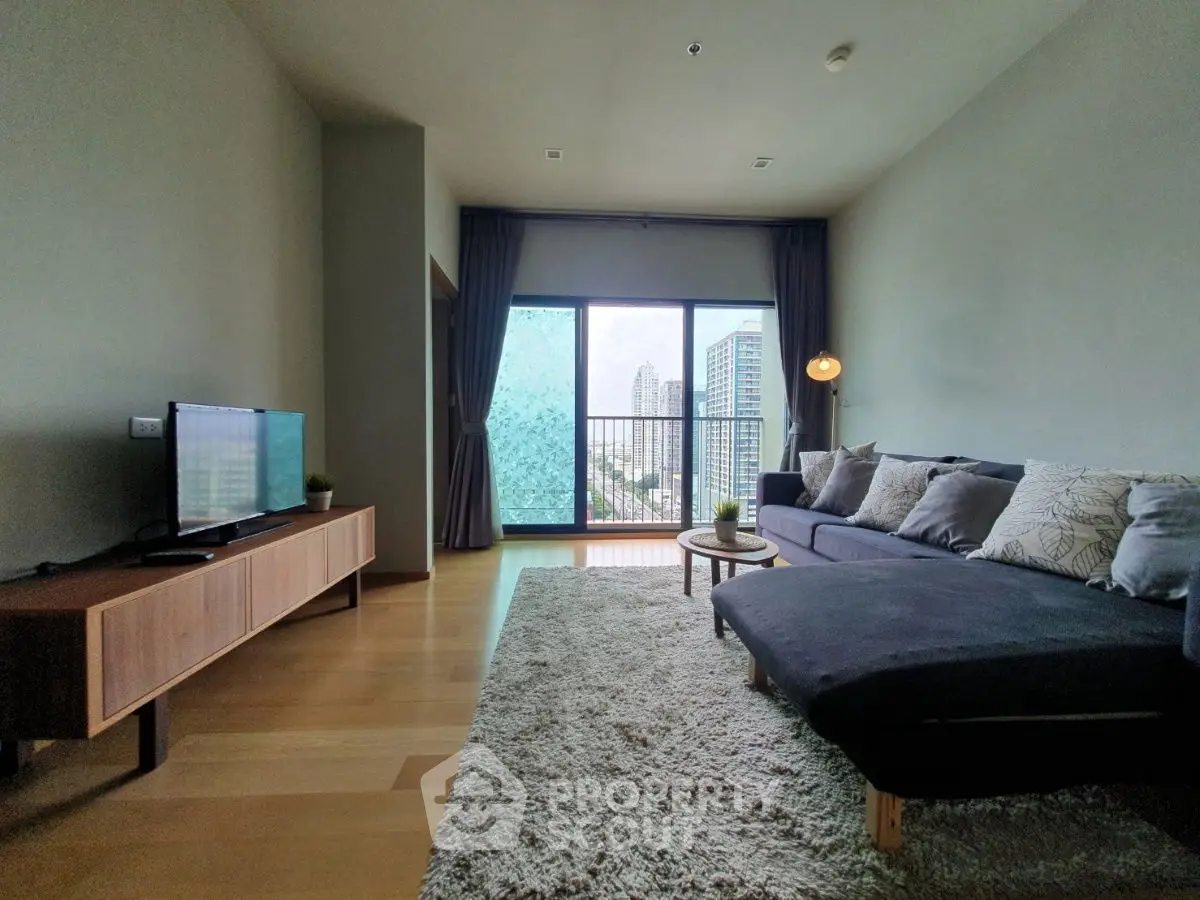 Modern living room with large window and city view, featuring stylish furniture and cozy decor.