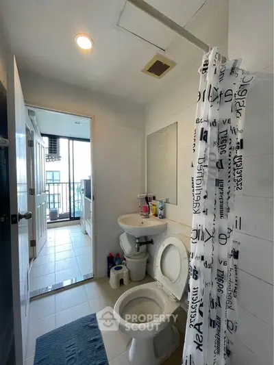 Modern bathroom with shower curtain and balcony view, featuring sleek fixtures and bright lighting.