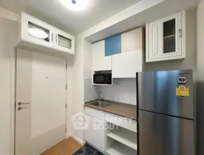 Modern compact kitchen with sleek cabinetry and stainless steel fridge