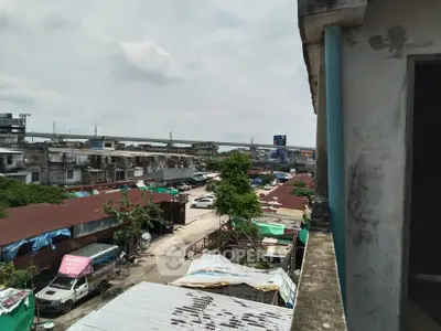 Urban view from a building showcasing a bustling street with vehicles and rooftops.