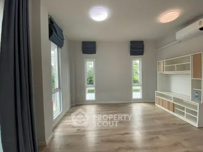Spacious modern living room with large windows and stylish shelving unit.