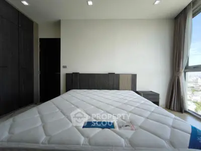 Modern bedroom with large window and city view, featuring a spacious bed and sleek wardrobe.