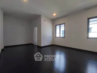 Spacious empty room with dark flooring and large windows, ideal for customization.