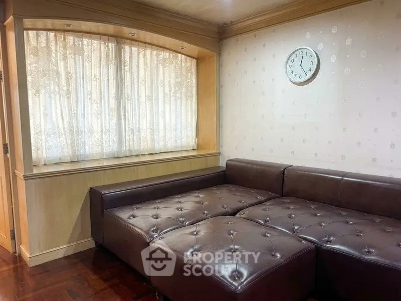 Cozy living room with brown leather sectional sofa and wall clock