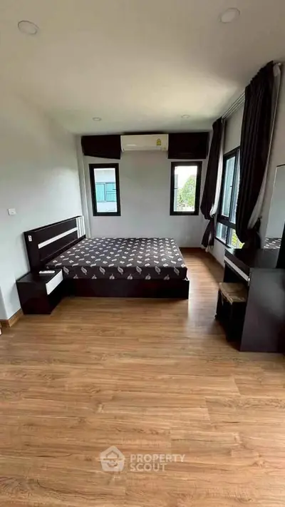 Spacious bedroom with modern furnishings and large windows for natural light.