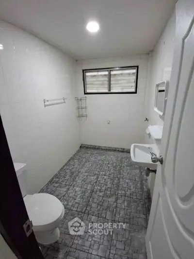 Spacious bathroom with modern fixtures and tiled flooring in a well-lit apartment.