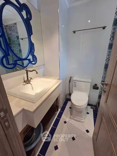 Charming bathroom with elegant sink and modern toilet in stylish blue and white decor.