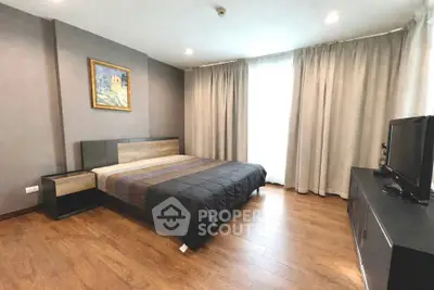 Spacious modern bedroom with wooden flooring and stylish decor