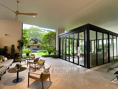 Luxurious open-plan living area with garden view and modern glass enclosure.