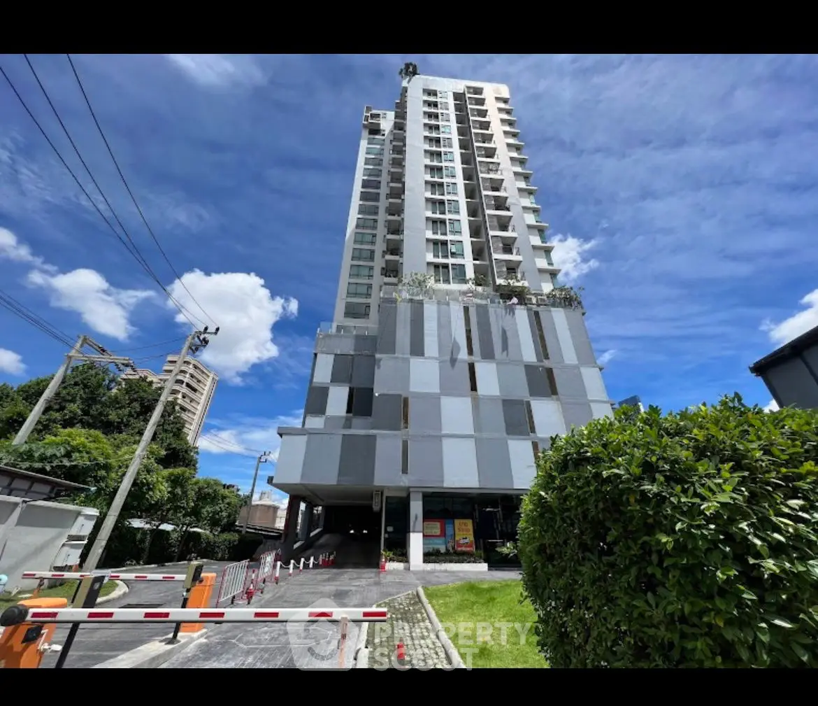 Modern high-rise building with lush greenery and clear blue sky, ideal urban living.