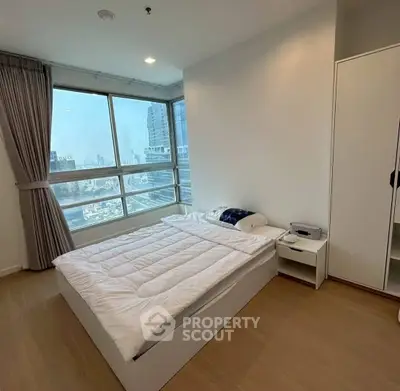 Modern bedroom with large windows offering city views and minimalist decor.