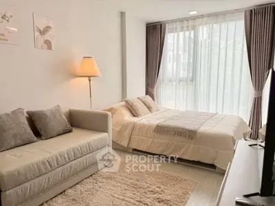 Cozy bedroom with elegant decor, featuring a plush bed, stylish sofa, and large window with sheer curtains.