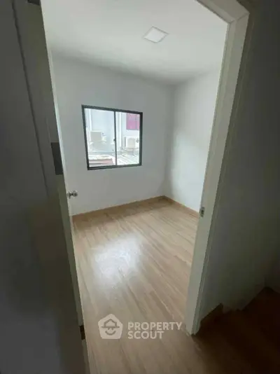 Cozy small room with wooden flooring and a bright window view.