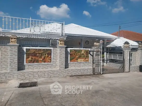 Charming single-story home with decorative wall art and gated entrance under a clear blue sky.