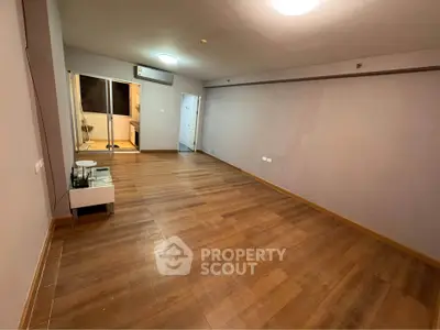 Spacious empty room with wooden flooring and modern lighting