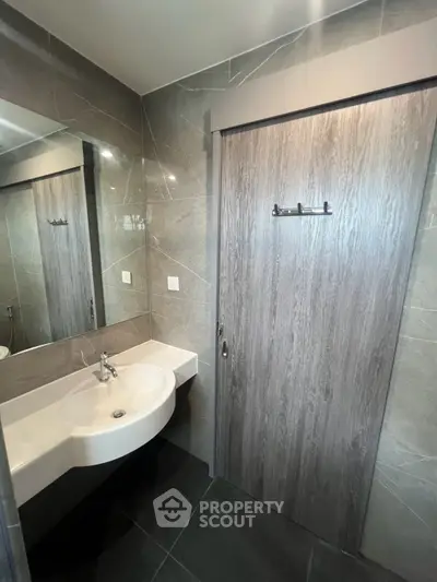 Modern bathroom with sleek sink and stylish wooden door in contemporary design.