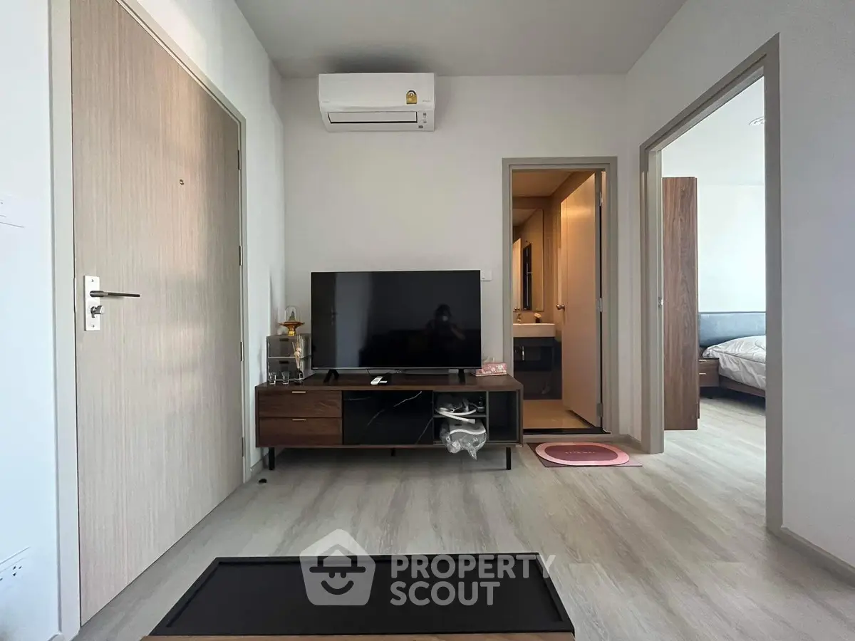 Modern living room with TV, air conditioning, and wooden flooring in a cozy apartment.
