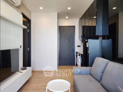 Modern living room with sleek furniture and compact kitchen in stylish apartment.