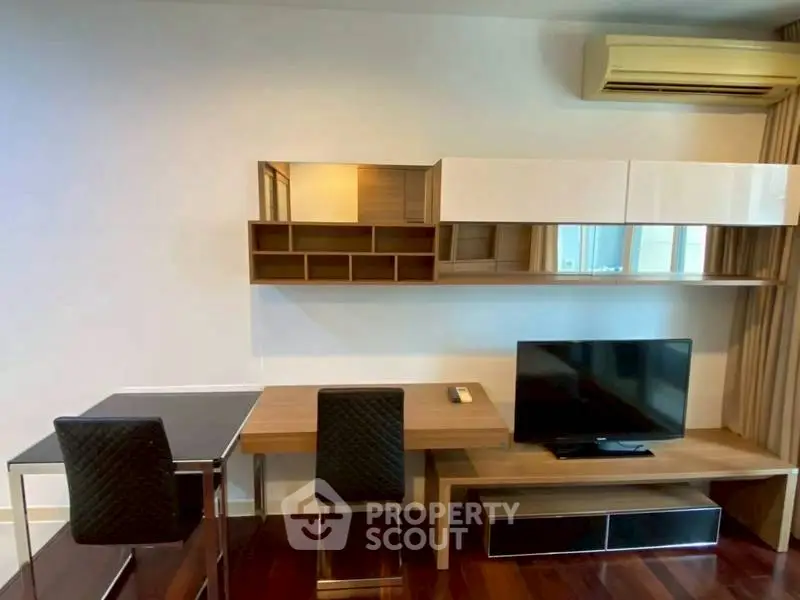 Modern living room with sleek furniture and wall-mounted TV, featuring a stylish work desk and air conditioning.